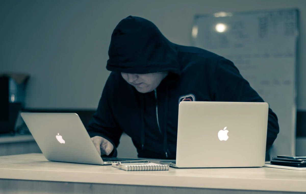Man in black using two notebook computers
